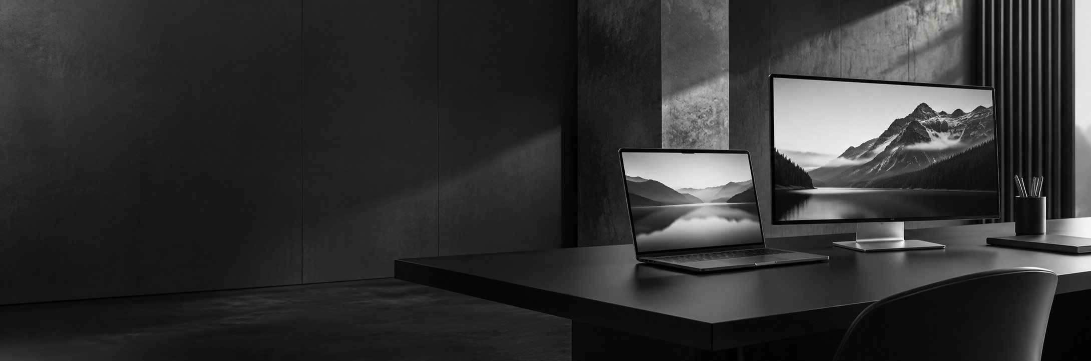 A monochrome workspace illustration with a laptop and monitor on a sculptural desk
